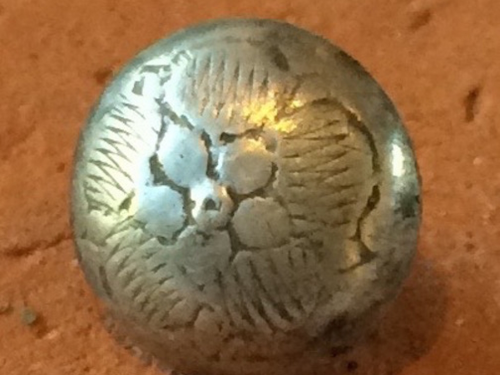 Een zilveren keelknoopje met bloemmotief
